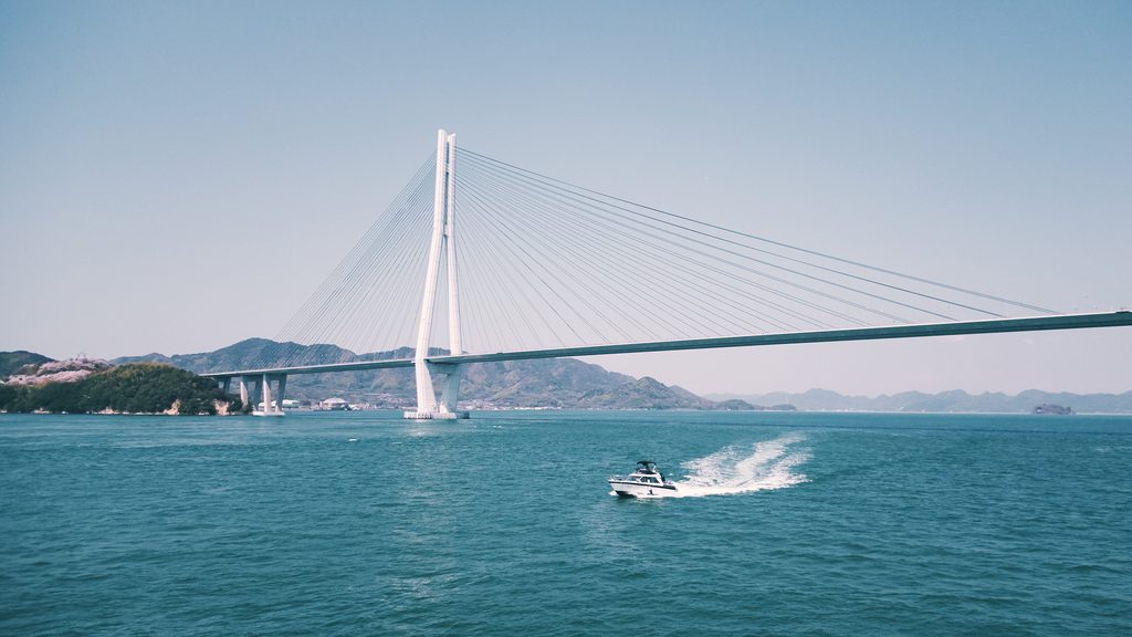 A motorboat crossing the Seto Inland Sea near Tatara Bridge, which connects Ikuchijima and Omishima islands along the Shimanami Kaido.