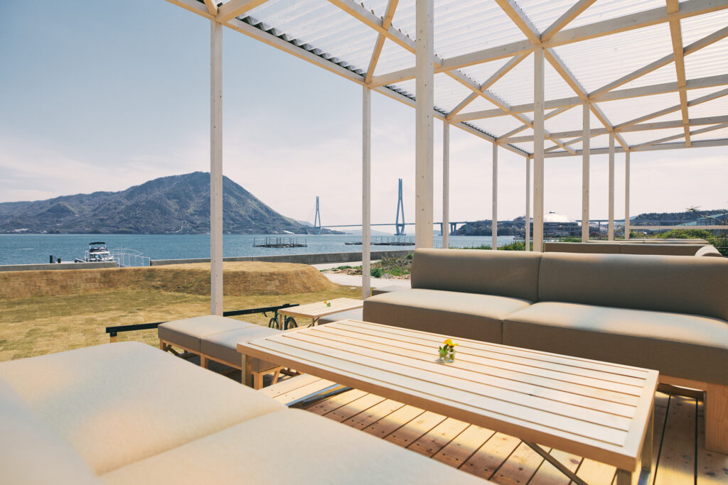 Outdoor café terrace at WAKKA on Omishima, with seating overlooking the Seto Inland Sea and Tatara Bridge.