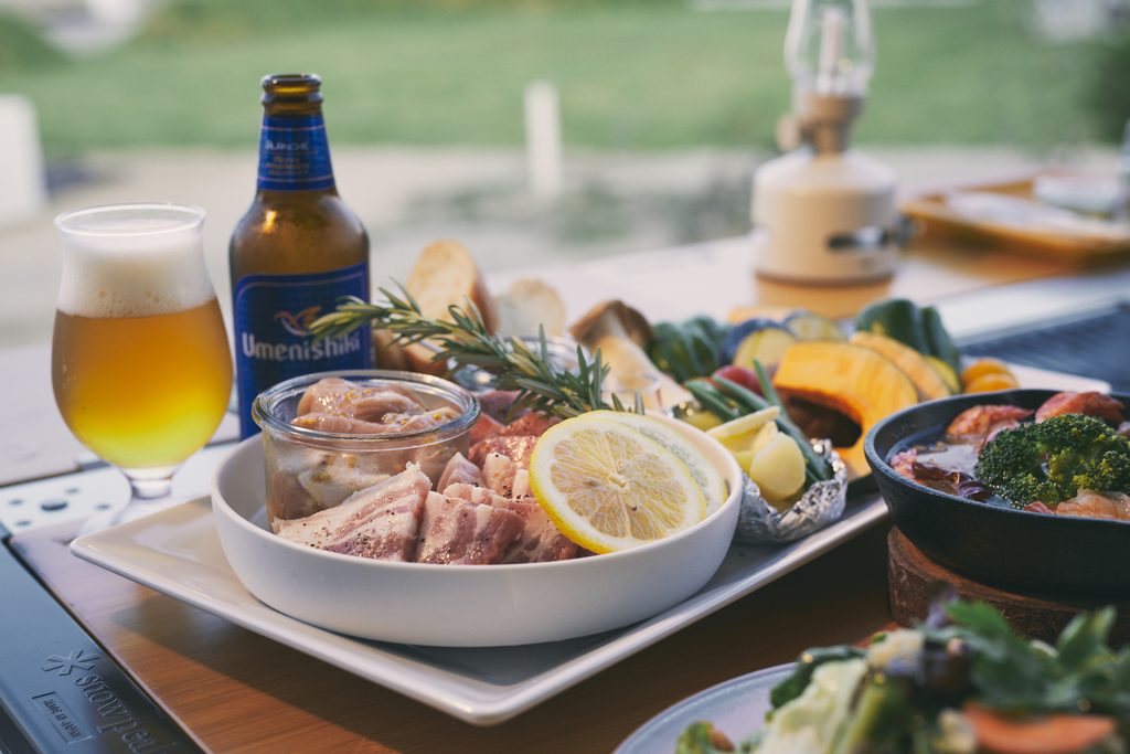 A dinner featuring seafood, vegetables, and beer served outdoors at WAKKA on Omishima.